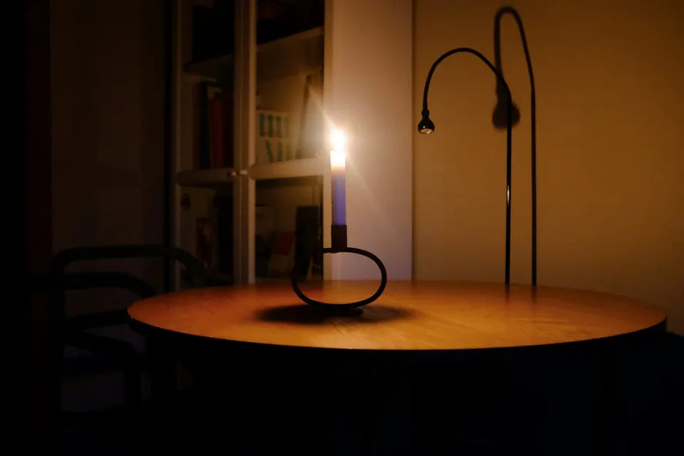 Een brandende kaars op een tafel in een donkere kamer